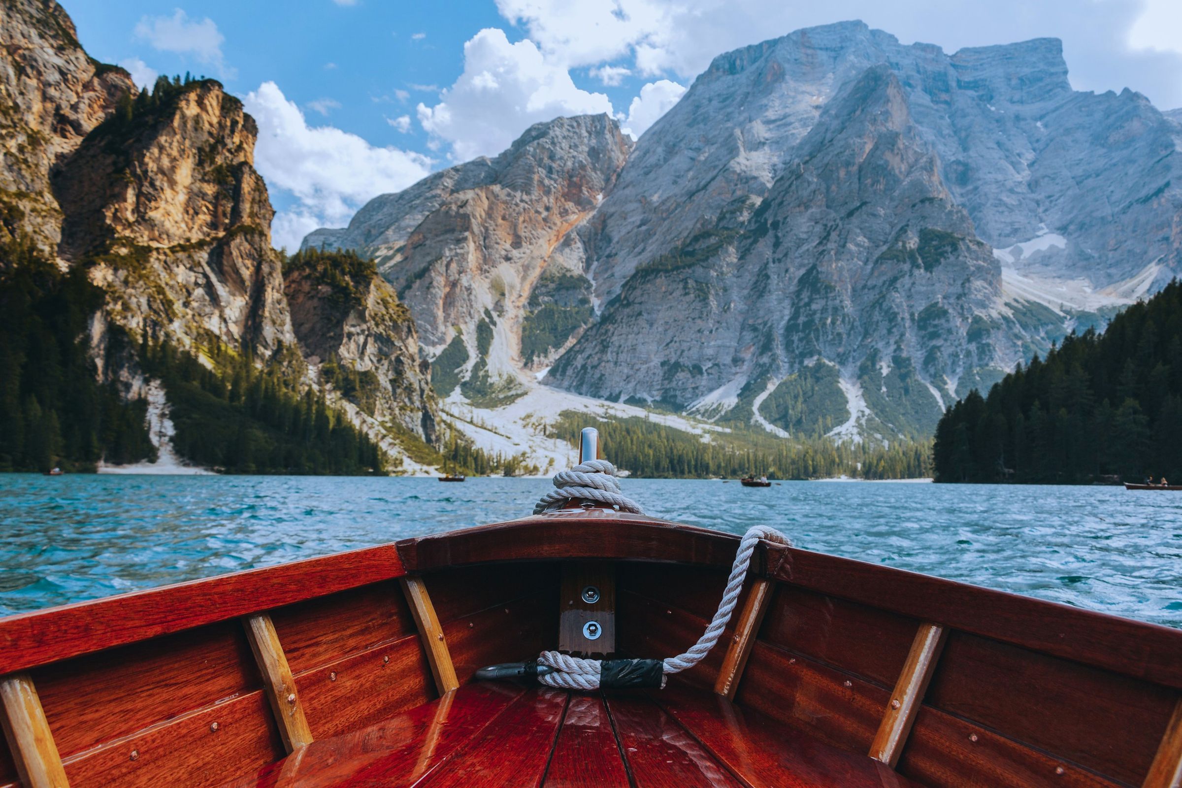 Proue d'une barque en bois sur un lac turquoise au pied des Dolomites